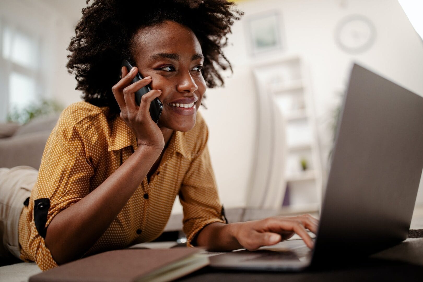 Student studying at home, working with her laptop computer and having phone call.